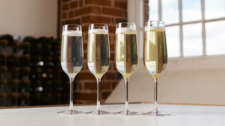Four flute glasses of sparkling wine lined up on a table showing different types of sparkling wine