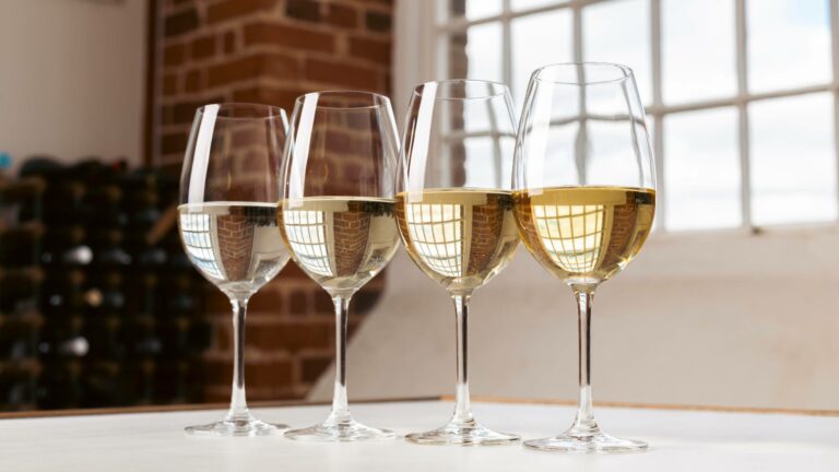 Four glasses of white wine lined up on a table showing different types of white wine
