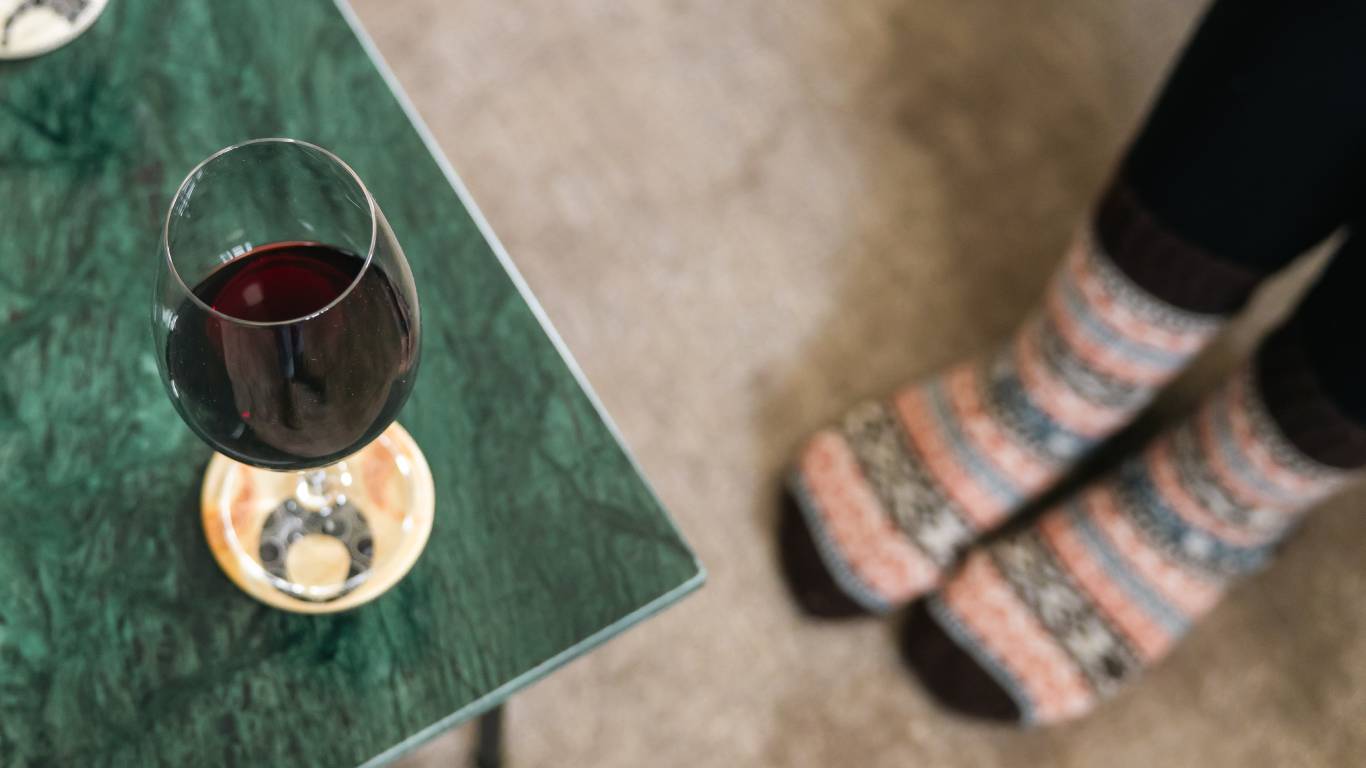 Woman in cosy socks next to a coffee table with red wine on it to represent best red wines for autumn winter