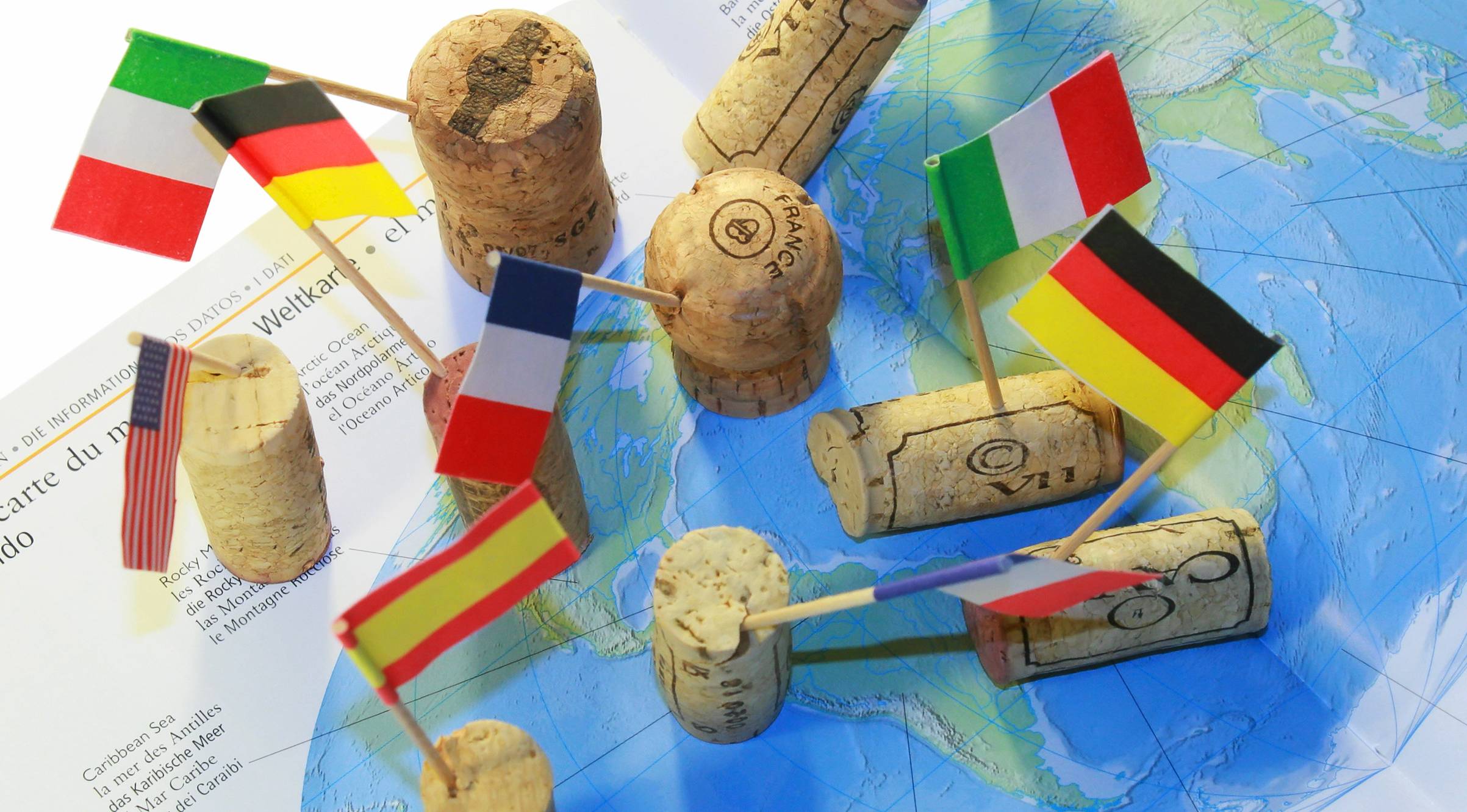 Several wine corks scattered on a world map with flags in them