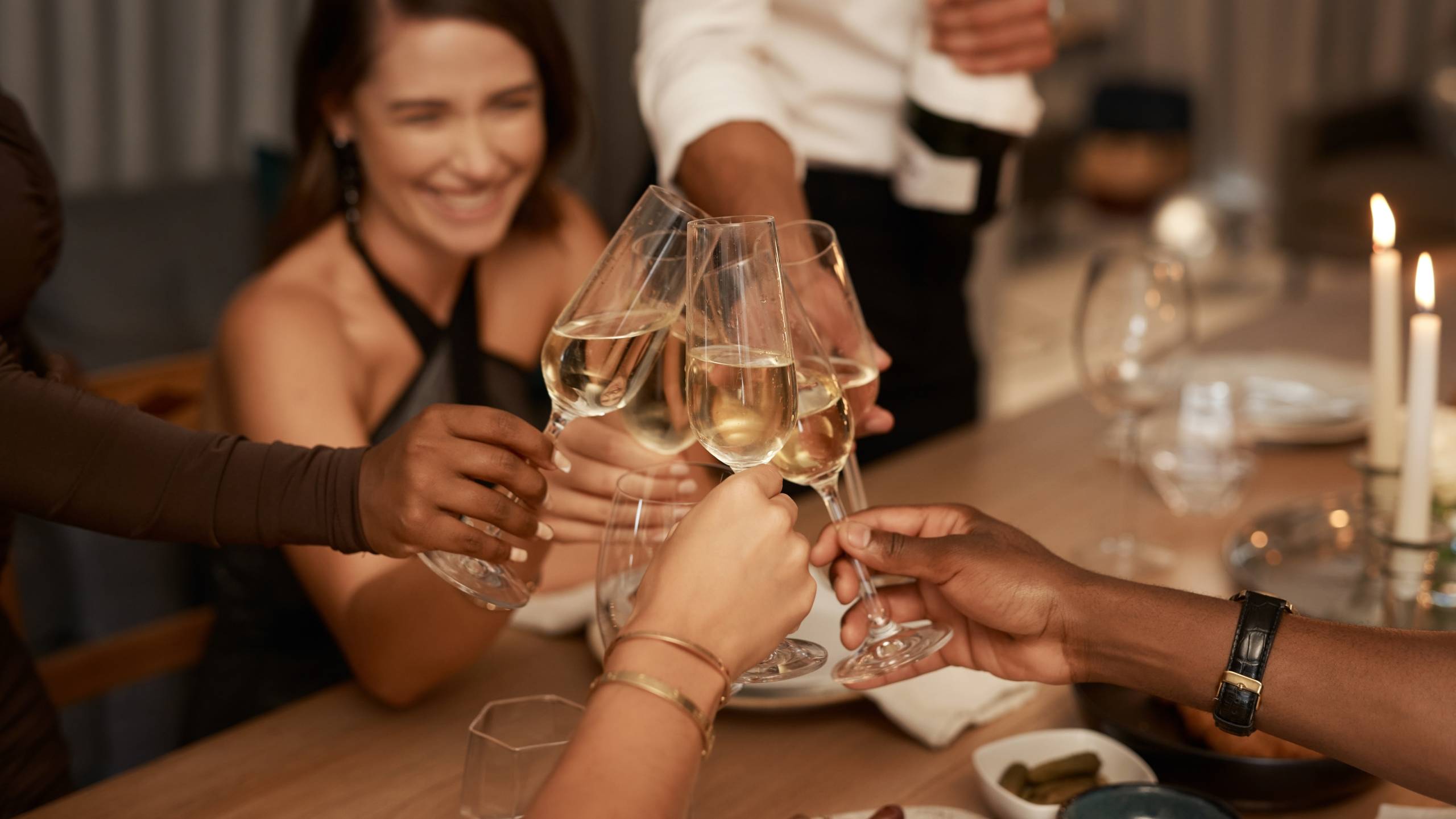 Group of people clinking Champagne flute glasses at a dinner party