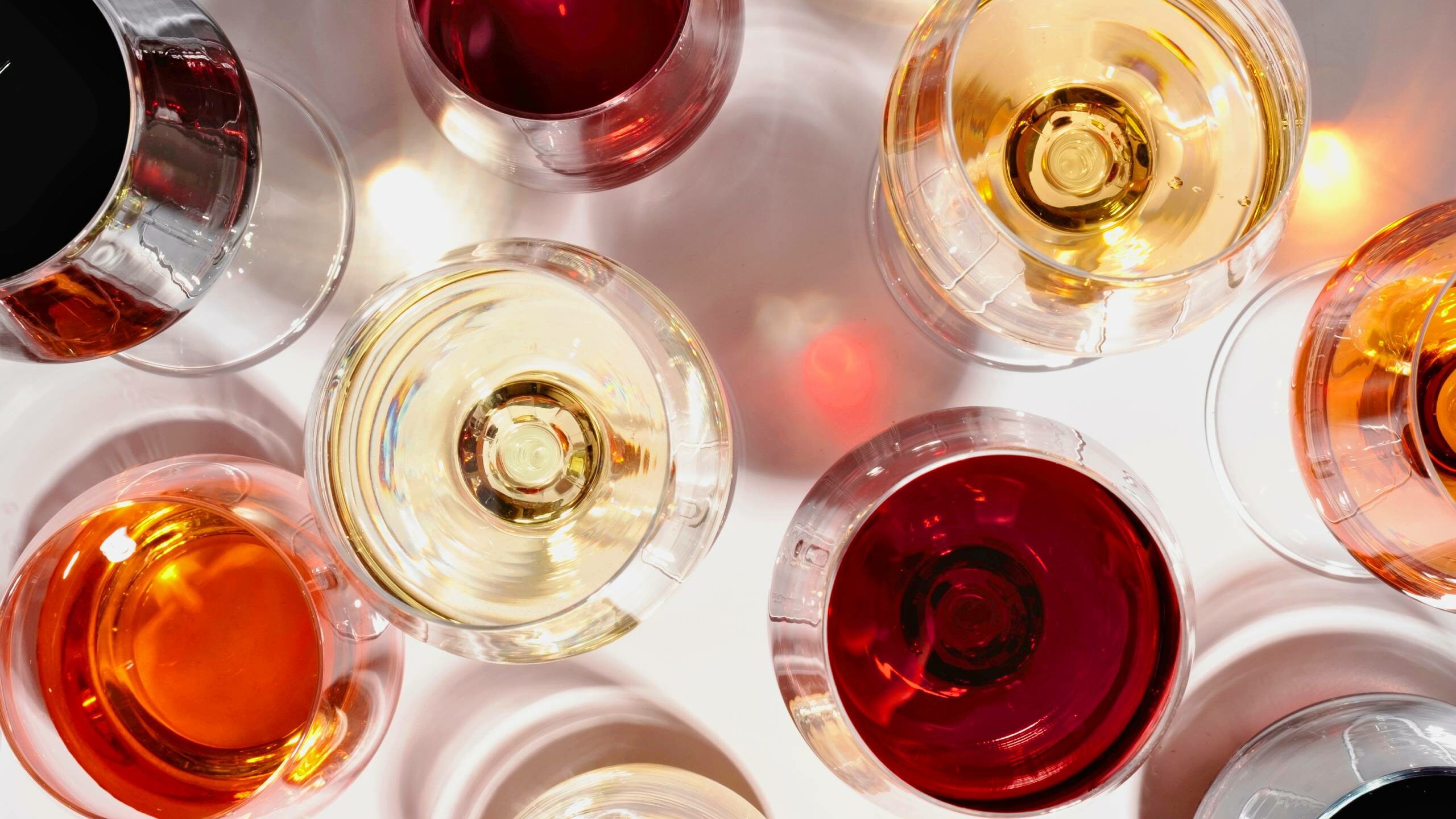 Glasses of red, white and rose wine on a white surface showing all the different colours of wine