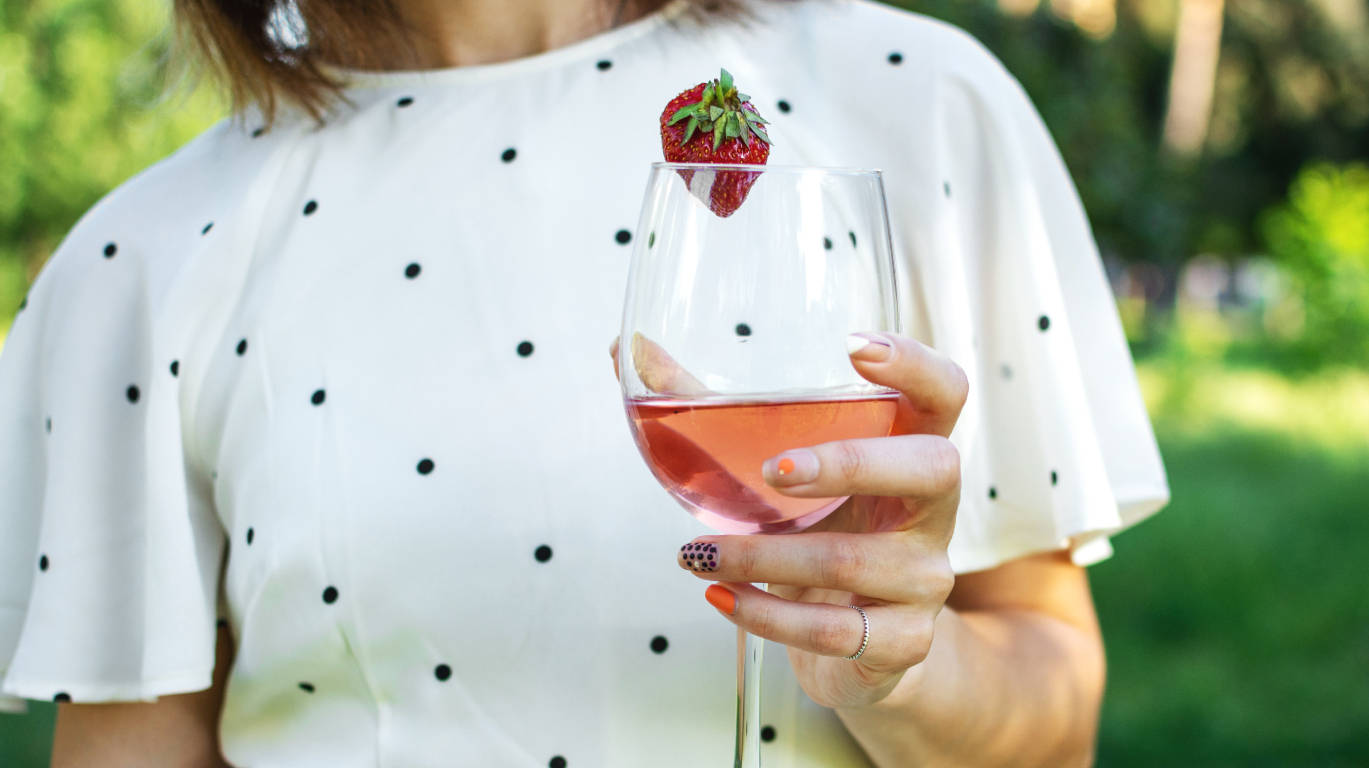 Woman holding a glass of rose wine on a sunny day outside