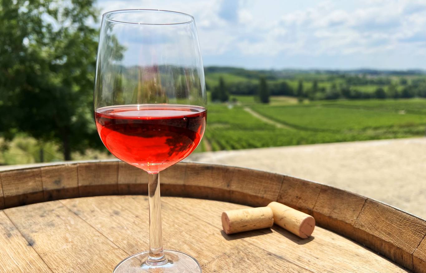 Glass of clairet wine on an oak barrell overlooking the vineyards of Chateau Cassat in AOC Puisseguin St Emilion, Bordeaux