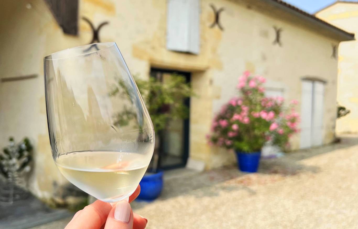 Woman holding a chilled glass of white wine outside Chateau La Lande De Taleyran in AOC Bordeaux and Entre-Deux-Mers, France