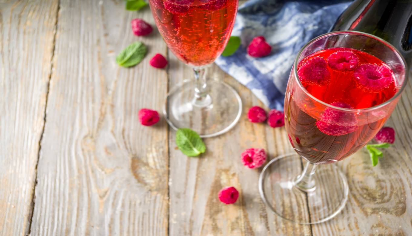 Kir Royale cocktail in champagne flute with fresh raspberry