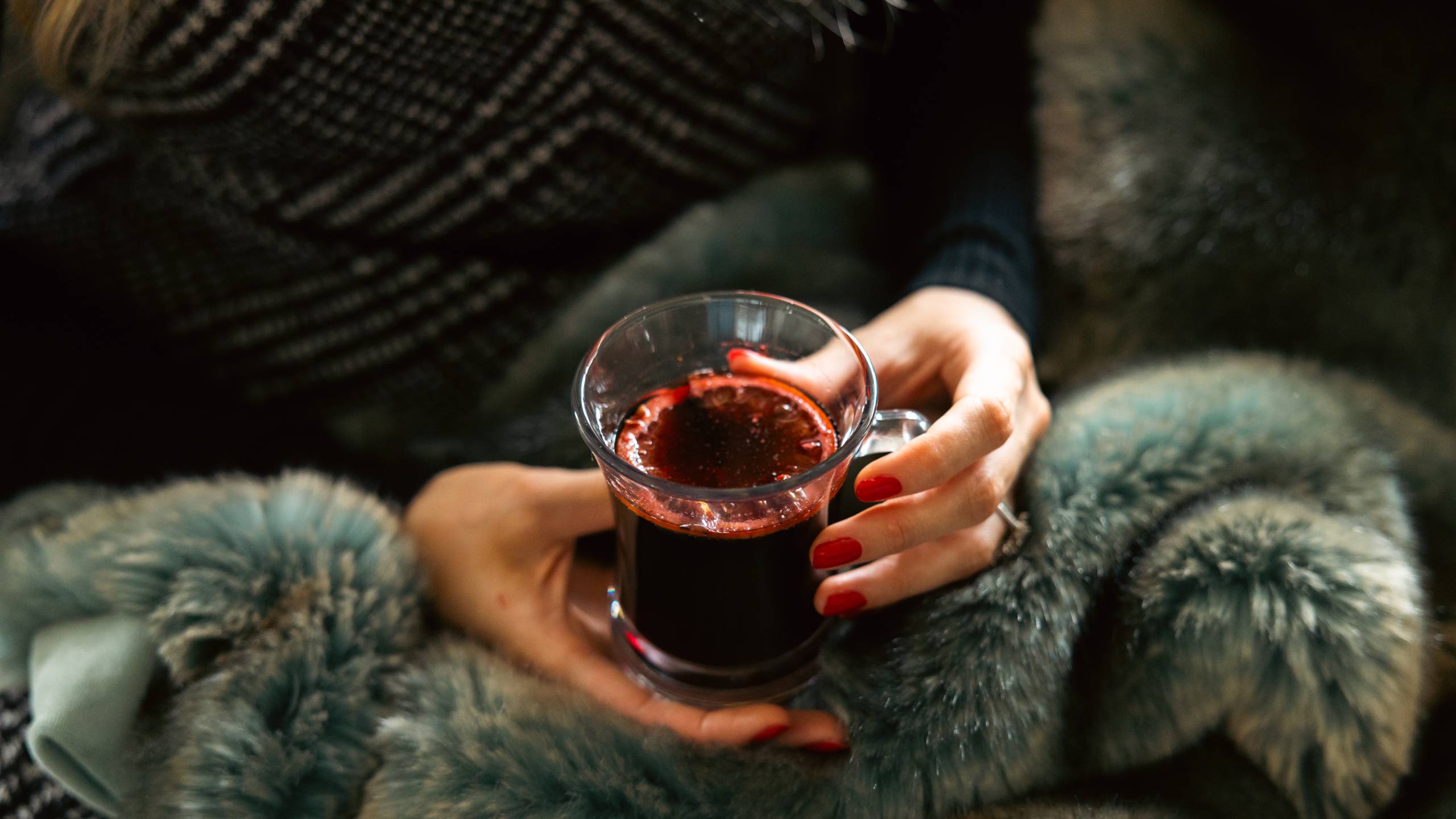 https://www.virginwines.co.uk/hub/wp-content/uploads/2023/11/Woman-enjoying-a-glass-of-mulled-wine-on-the-sofa-to-represent-Christmas-mulled-wine-recipe.jpg
