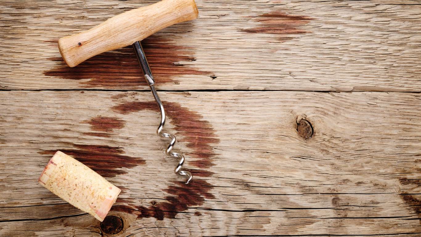 Corkscrew and cork on wooden table to represent corked wine
