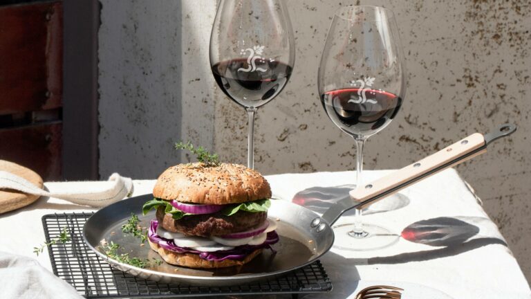 Two glasses of red wine and a burger in the sunshine to represent Rioja wine and food pairing