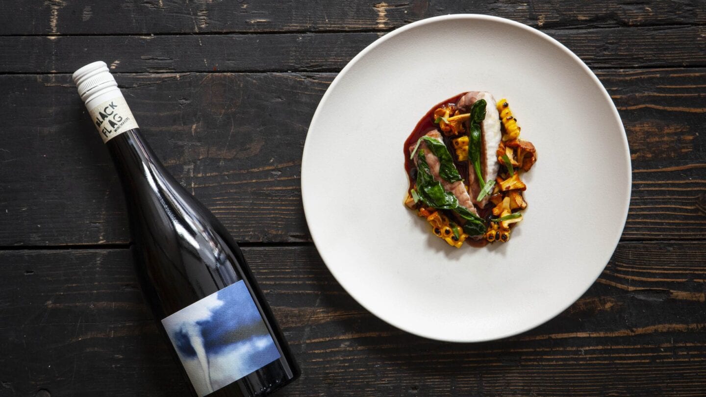 Red wine-poached monkfish with corn, girolles and black garlic with Black Flag Pinot Noir