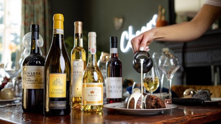 Selection of dessert wines and cream being poured over a Christmas Pudding